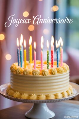 Gâteau d'anniversaire jaune pâle avec glaçage texturé, décoré de bougies allumées multicolores sur un support blanc.