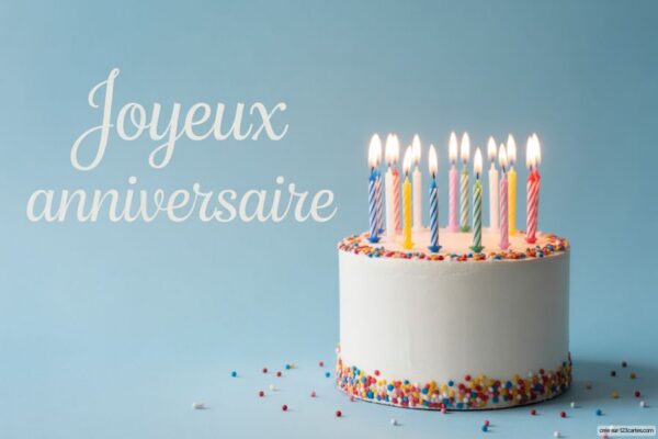 Gâteau d'anniversaire blanc avec bougies allumées multicolores et vermicelles colorés, sur fond bleu clair.