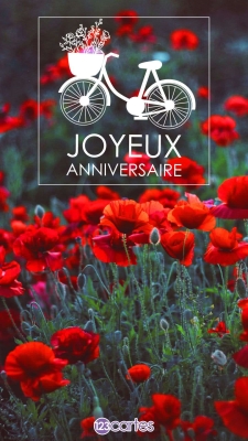 Carte d'anniversaire avec vélo blanc et fleurs rouges sur fond de champs de coquelicots. Texte Joyeux Anniversaire.