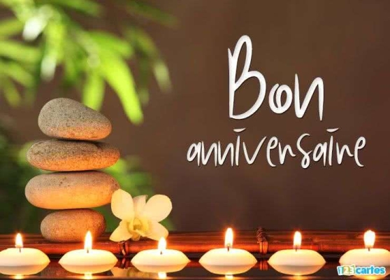 Pierre empilée avec orchidée et bougies allumées sur fond flou vert, texte Bon anniversaire en blanc. Ambiance zen.
