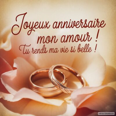 Deux alliances posées sur une fleur rose, avec le message Joyeux anniversaire mon amour ! Tu rends ma vie si belle !