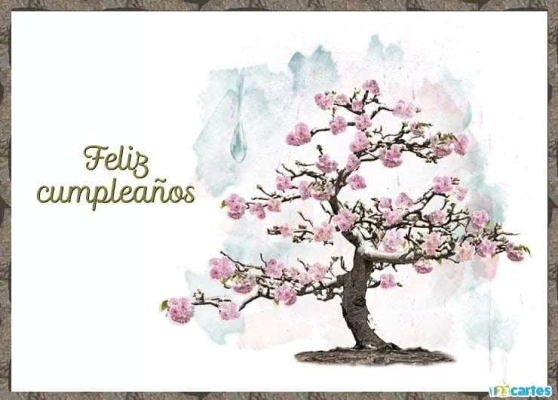Texte en espagnol Feliz cumpleaños à gauche, avec un arbre en fleurs roses sur un fond aquarelle.