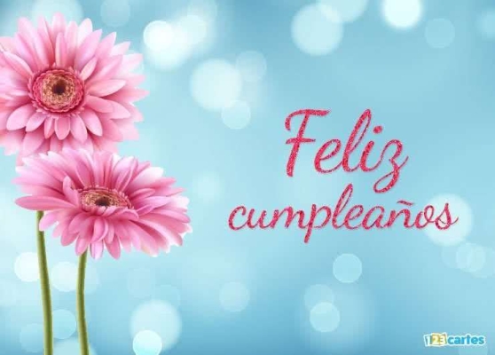 Fleurs roses sur fond bleu avec texte en espagnol « Feliz cumpleaños » en rose scintillant.